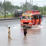 Vehicles passing through the stagnant water at IJP Road during heavy rain in Federal Capital