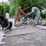 Laborers busy fixing tuff tiles on a footpath in the Federal Capital