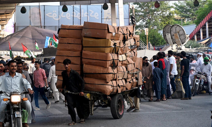 A labourer on the way pulling a heavily loaded handcart to deliver the stuff to shops at Liaquat Bagh