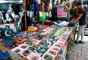Vendor displaying national flag badges and other festive items to attract customers ahead of the upcoming Independence Day celebrations at G 9 in the Federal Capital.