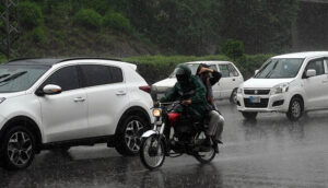 Vehicles and bikers make their way through heavy rain at Zero Point in the Federal Capital