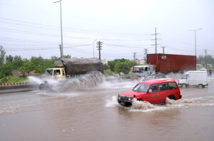Vehicles passing through the stagnant water at IJP Road during heavy rain in Federal Capital