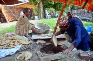 A person making bread (roti) in a traditional oven (Tandoor).