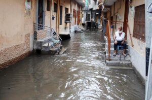 An elderly man sits on the stairs, observing rainwater accumulating in the street after a downpour in Amarpura,in the twin cities.