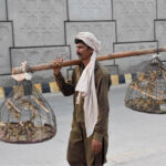 A vendor selling sparrows to attract customers while shuttling on the road