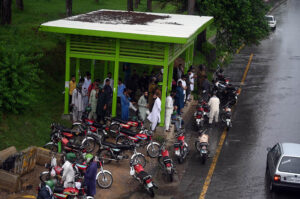 Motorcyclists take shelter at a bus terminal at Zero Point during heavy rain in the Federal Capital