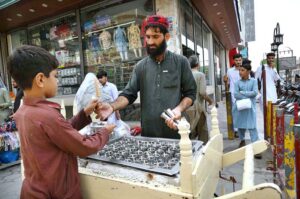 A Vendor selling traditional ice-cream "Kufi'' to customer at Cantt Bazaar.