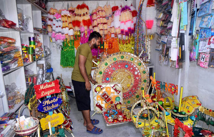 A vendor displays traditional mehndi thaal and other stuff used for wedding functions at Sadiqabad