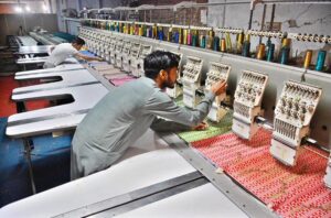 Worker busy align designs on fabric machines for precise printing at the local textile factory.