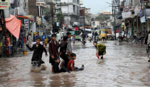 An elderly man sits on the stairs, observing rainwater accumulating in the street after a downpour in Amarpura,in the twin cities.