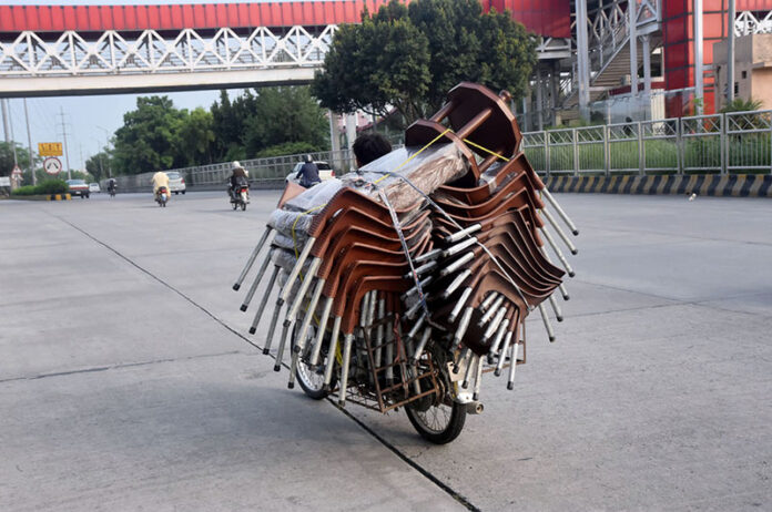 A vendor selling chairs while riding his motorbike at 9th avenue in the Federal Capital