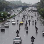 Vehicles and bikers make their way through heavy rain at Zero Point in the Federal Capital