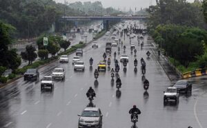 Vehicles and bikers make their way through heavy rain at Zero Point in the Federal Capital