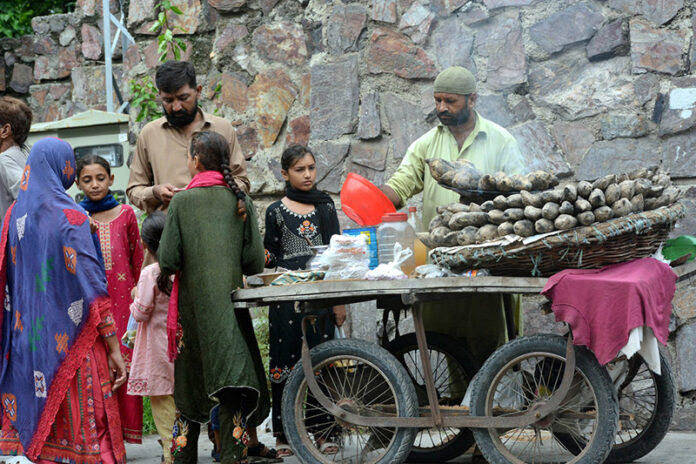 A vendor displaying roasted sweet potatoes (Shakarkandi) to attract the customers on roadside A vendor displaying roasted sweet potatoes (Shakarkandi) to attract the customers on roadside