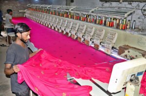 Worker busy align designs on fabric machines for precise printing at the local textile factory.