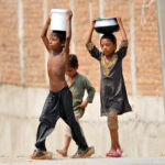 Children on their way back carrying pots after filling clean drinking water