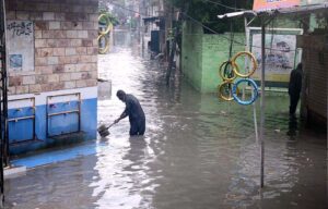 An elderly man sits on the stairs, observing rainwater accumulating in the street after a downpour in Amarpura,in the twin cities.