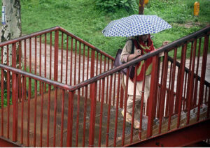 Motorcyclists take shelter at a bus terminal at Zero Point during heavy rain in the Federal Capital