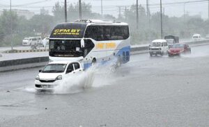 Vehicles passing through rainwater accumulated at IJP Road during heavy rain in Federal Capital.