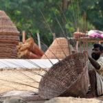 Artisan preparing a basket with dry tree branches to sell for livelihood at roadside