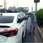 An elderly beggar begs from auto drivers near traffic junction on Jaranwala Road