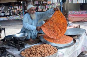 An elderly vendor prepares traditional Katlamas, a famous local delicacy,enticing customers with the savory aroma and authentic taste at his roadside stall
