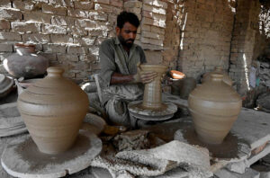 A worker arranging clay-made pitcher for drying purpose at his workplace at Kumharpara near Jamshoro road.
