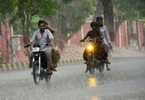 Gypsy women with children traveling on the tri-cycle rickshaw during rain in the city.