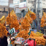 A vendor is busy displaying fresh dates to attract customers at his roadside setup