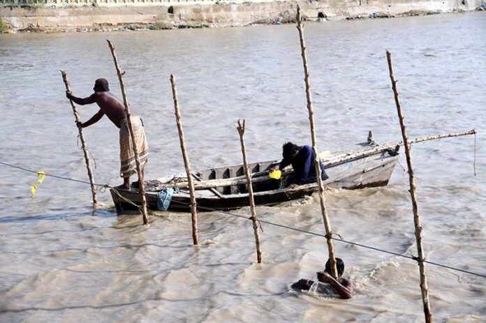 Fishermen engage in traditional technique of catching fish from their boats on the Rice Canal