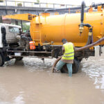 Workers of Municipal Corporation draining rain water in front of DHQ Hospital