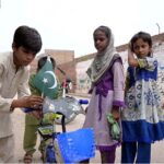 A patriotic child decorates his bicycle with a Pakistan flag in preparation for the upcoming Independence Day celebrations in Hyderabad