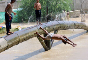 A youngster diving for bathing in water canal to get relief from hot weather in the city