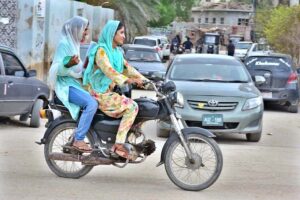 Girls with confidence enjoy their freedom of the open road, riding motorbikes through the streets of Latifabad.