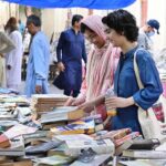 Women busy in selecting and purchasing old books from roadside stall at Mall Road