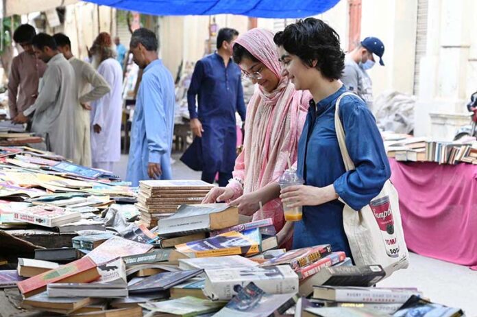 Women busy in selecting and purchasing old books from roadside stall at Mall Road