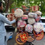 A vendor arranges handmade baskets on his bike to attract customers at a roadside in the Federal Capital