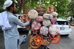 A vendor arranges handmade baskets on his bike to attract customers at a roadside in the Federal Capital