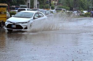 Vehicles passing through rainwater accumulated on road at College Road after heavy rain in the city.