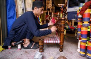 A youngster weaves a traditional chair at his workplace.