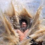A youngster diving for bathing in water canal to get relief from hot weather in the city