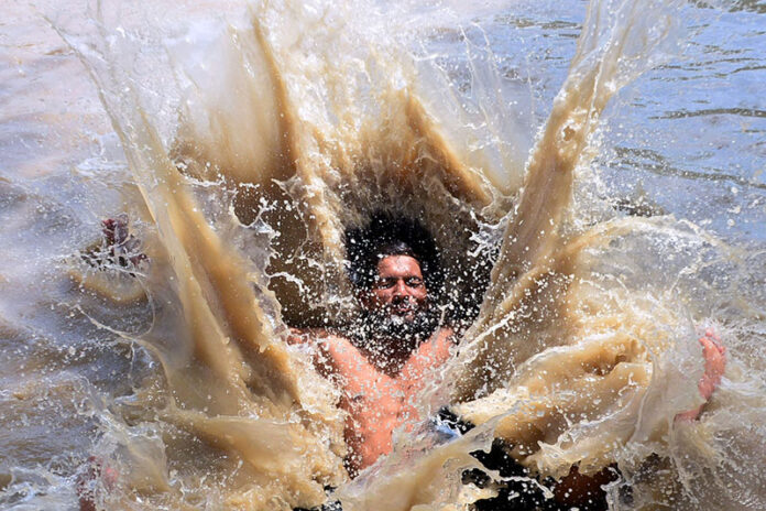 A youngster diving for bathing in water canal to get relief from hot weather in the city