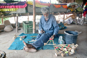 A nomadic man is making toys in his hut to earn for livelihood