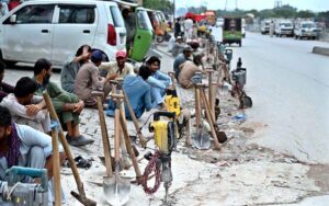 Laborers along with their tools are waiting to be hired for work while sitting at Khanna Pul.