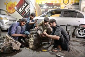 Mechanics busy in repairing vehicle’s engine in workshop at Tiwana Park.