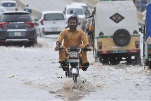 A motorcyclist passing through rainwater accumulated on the road after monsoon rain in the city