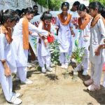 Students of school are showering water on the plant saplings during a plantation campaign at the Government anti-TB Hospital area in Latifabad