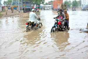 Motorcyclists passing through rain water accumulated on the Hali Road after heavy rain in the city.
