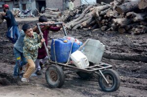 Children pushing hand cart loaded with water canes after filling clean water from filter.
