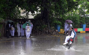 Female students wait for their college bus during a downpour in the Federal Capital